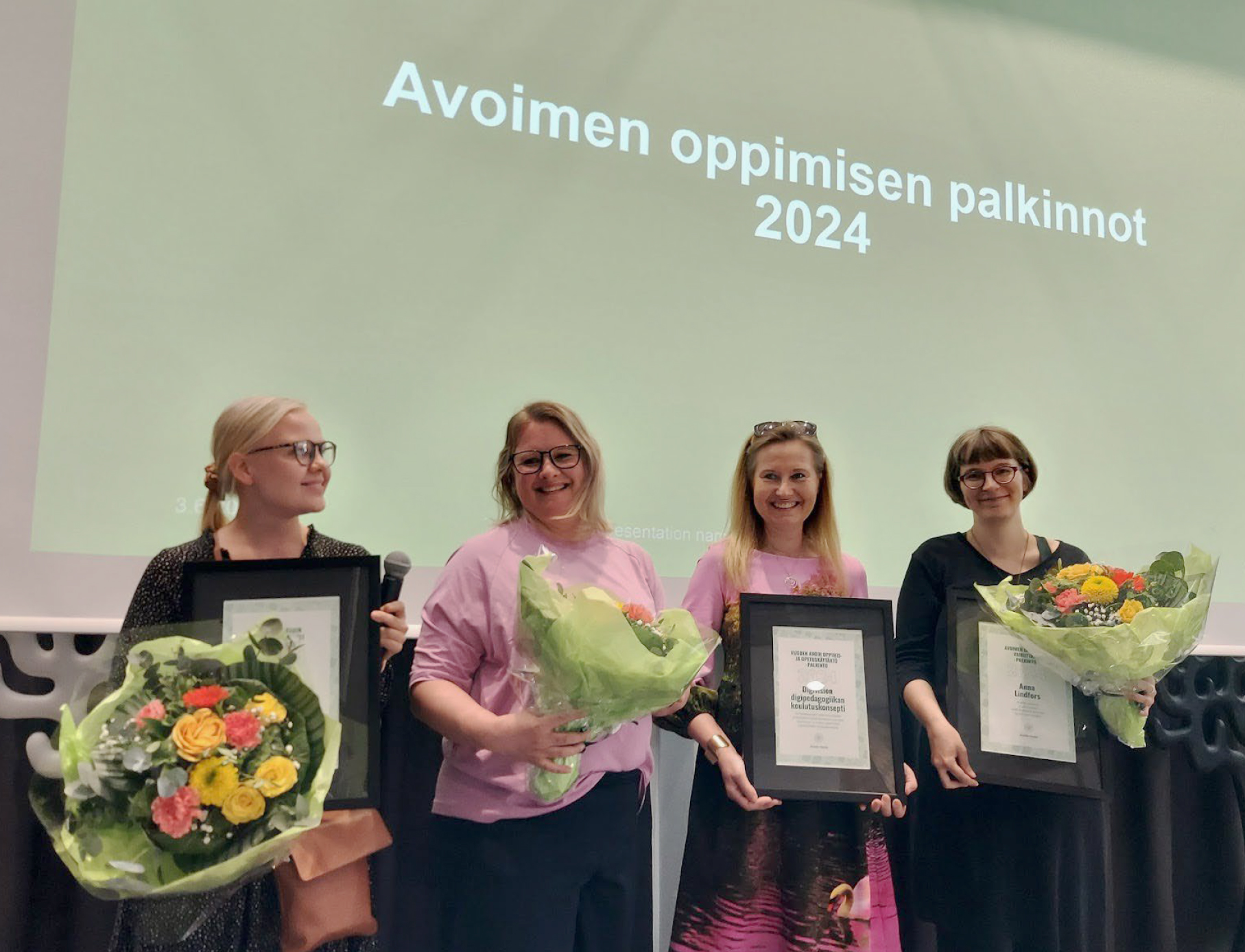 Avoimen oppimisen palkinnonsaajat lavalla Avoimen tieteen kesäpäivillä, kukkakimput ja kunniakirjat käsissään..