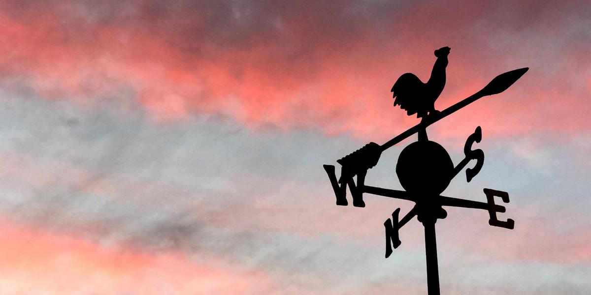 Weather vane against pink sky