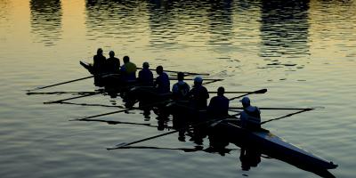 Soutuvene jossa yhdeksän soutajaa hämärässä vesillä. Rowing boat with nine rowers afloat at dusk..