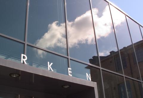 Åbo Akademin rakennus Arken, jonka lasisessa julkisivussa heijastuu pilvi sinisellä taivaalla.