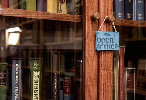 Kuvituskuva. Lasinen kirjakaappi, jossa lukee "open me". 