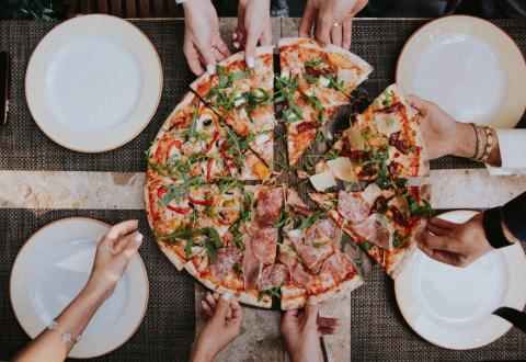 Ihmisiä jakamassa pitsaa.